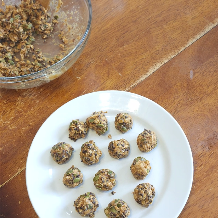 Peanut Butter Snack Balls on a plate next to a mixing bowl on a table.
