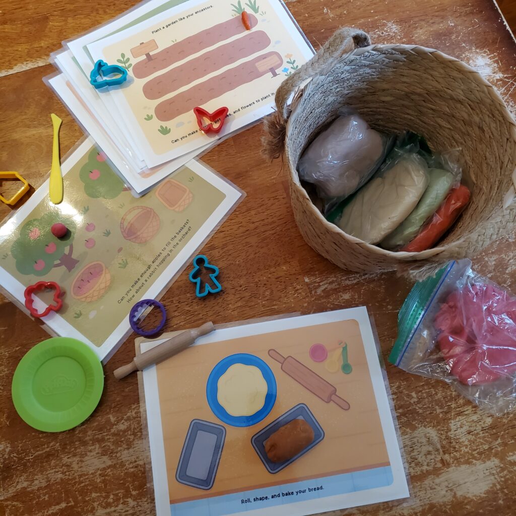 Hands-on family history playdough mats and tools next to a basket of playdough on a wooden table.