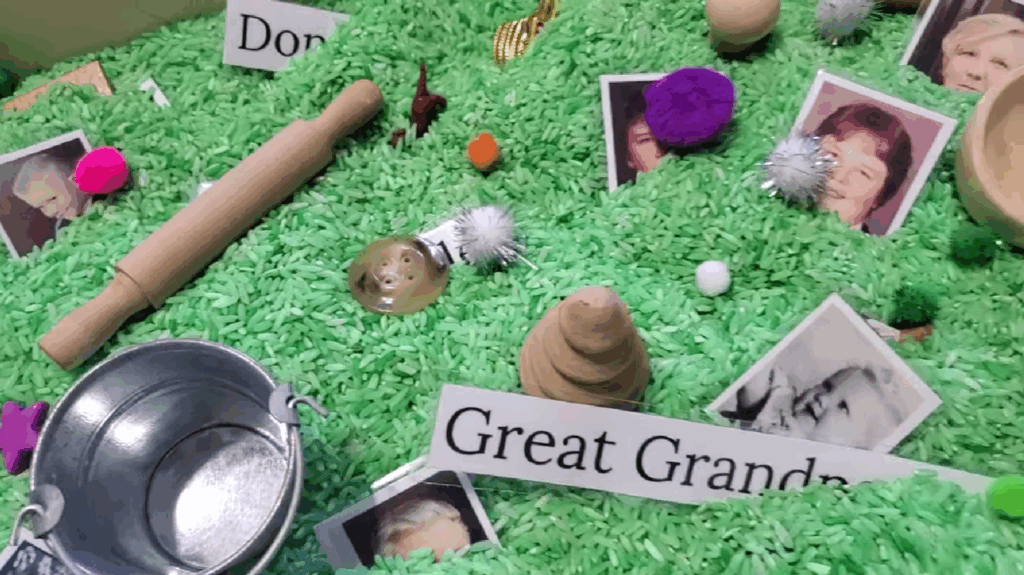 Nostalgia evoking items and pictures of ancestors nestled in green grains of rice encouraging hands-on family history.
