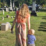 Young woman guiding toddler with cemetery etiquette for families